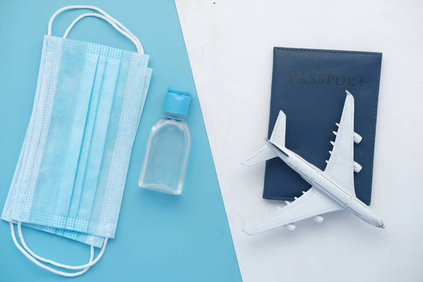 máscara protetora, avião e passaporte de cor azul na mesa  - Foto, Imagem
