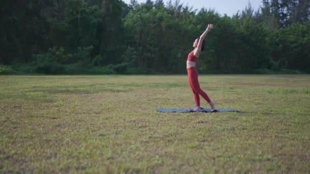 Ruční záběry asijské číňanky žena jóga strečink otevřené pole - Záběry, video