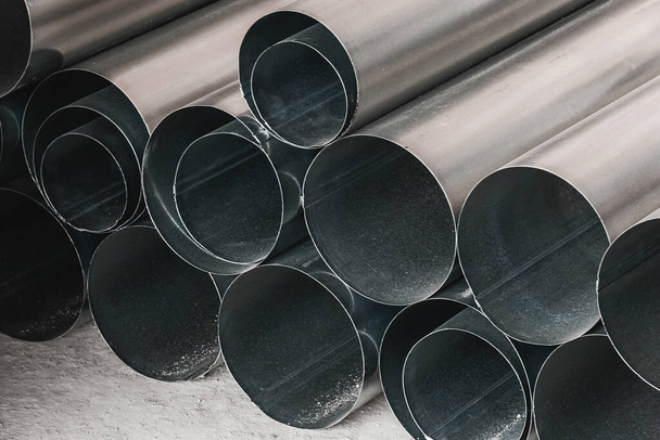 Montón de tubos metálicos redondos en una obra de construcción. Almacenamiento de materiales industriales de tubos de acero en almacén - Foto, Imagen