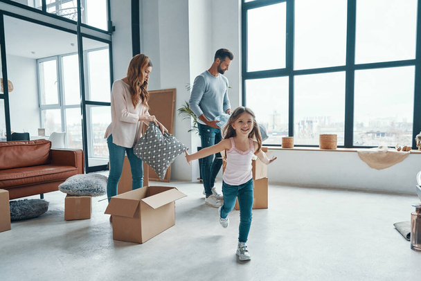 Happy young family smiling and unboxing their stuff while moving into a new apartment - Foto, imagen