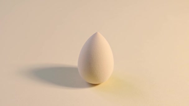 Cosmetic sponge beauty blender on a beige background rotating. - Footage, Video