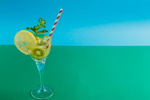 Kiwi cocktail garnished with lemon and mint in a glass on a napkin on a green background. - Foto, Imagen