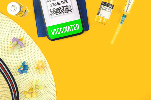 Χώρος εργασίας για ταξίδια κατά τη διάρκεια covid πανδημία coronavirus, κορυφαία προβολή και επίπεδη lay φόντο φωτογραφία με εμβόλιο και διαβατήριο υγείας στην οθόνη του smartphone - Φωτογραφία, εικόνα