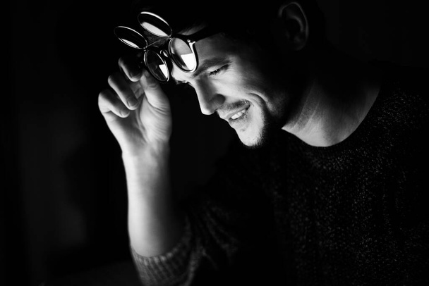 Černobílá fotografie; portrét mladého usmívajícího se muže s kulatými brýlemi. - Fotografie, Obrázek
