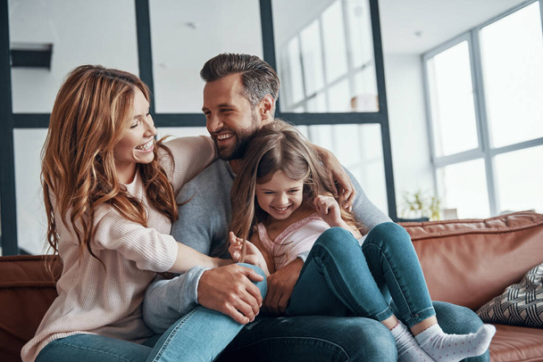 Happy young family smiling and embracing while bonding together at home - Φωτογραφία, εικόνα
