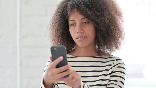 Африканська жінка використовує смартфон, переглядаючи Інтернет
 - Фото, зображення