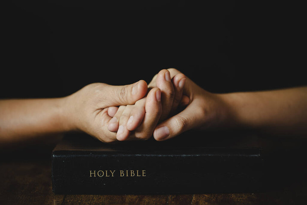 Die Hände gefaltet im Gebet an einer Heiligen Bibel in der Kirche Konzept für Glauben, Spiritualität und Religion, Frau betet auf der Heiligen Bibel am Morgen. Frauenhand mit Bibelgebet. - Foto, Bild