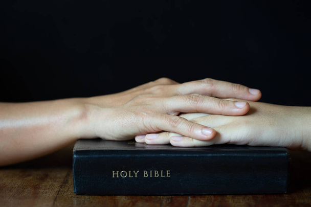 Ręce złożone w modlitwie na Biblii w koncepcji kościoła dla wiary, duchowości i religii, kobieta modli się na świętej Biblii rano. kobieta ręka z Biblią modląc. - Zdjęcie, obraz