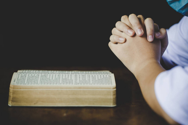 信仰、霊性、宗教のための教会の概念の聖書に祈りの中で折り畳まれた手、午前中に聖書の上で祈る女性。聖書を祈る女性の手. - 写真・画像