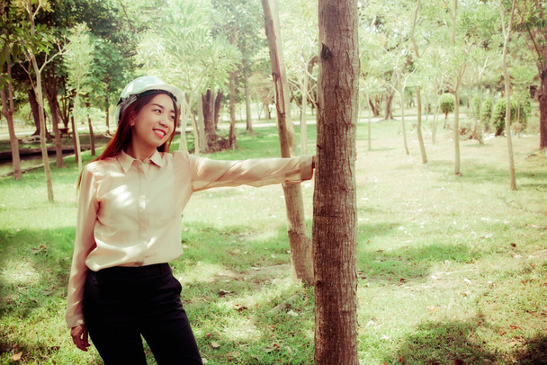 Женщина-архитектор посмотрела на ствол дерева, осознавая важность защиты окружающей среды и зеленого пространства дерева для хорошего здоровья в зеленой зоне летом: - Фото, изображение