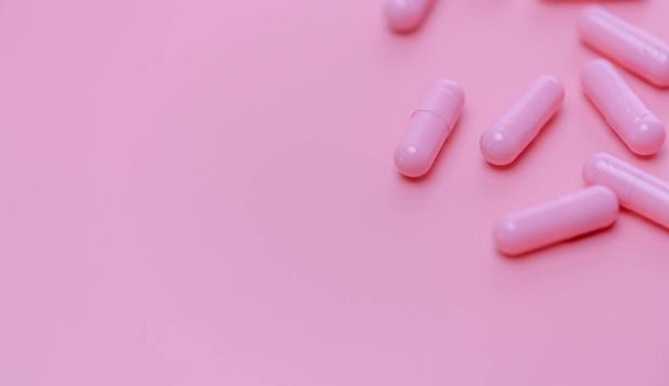 ピンクのカプセルはピンクの背景に丸薬。ビタミンやサプリメント。オンライン薬局。薬局のバナー。製薬業界。女性の健康保険の概念。愛と幸せな生活のための薬. - 写真・画像