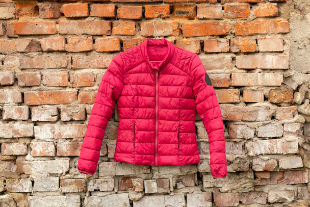 red women's jacket weighs on hangers on the wall at home on the street, women's jacket fashion - Photo, Image