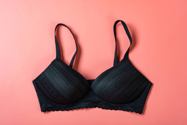 outside of a black bra for women on a pink background - Фото, изображение