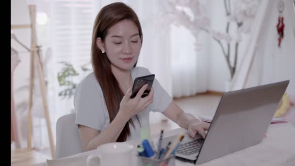 Mujer asiática de negocios Hablar con el trabajo por teléfono y tomar notas en el ordenador portátil con el trabajo desde casa. - Metraje, vídeo