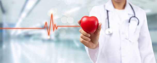 Sağlık sigortası konsepti için kalp hastalığı hastanesi odası için kırmızı kalp tutan doktorun elini kapatın. - Fotoğraf, Görsel