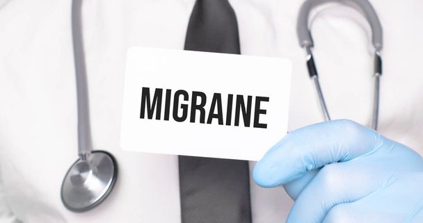 Doctor holding a card with text MIGRAINE,medical concept - Foto, Imagen