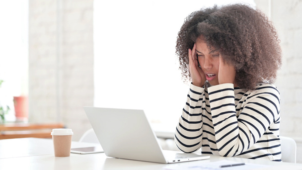 Femme africaine stressée avec ordinateur portable ayant mal à la tête  - Photo, image