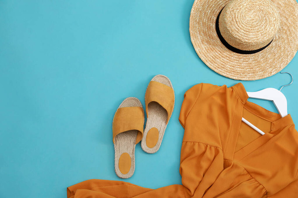 Dress, straw hat and shoes on light blue background, flat lay with space for text. Clothes rent concept - Фото, изображение