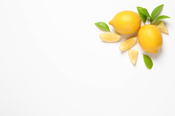 Whole and cut lemons with leaves on white background, top view - Foto, Imagem