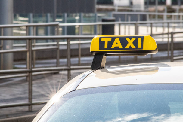 Taxi mit gelbem Schild auf dem Dach an einem glänzenden Tag wartet auf Passagiere und Touristen, um zum Flughafen oder nach Hause zu fahren als flexibler Transport in städtischen Städten und Straßen auf Reisen und europäische Mobilität - Foto, Bild