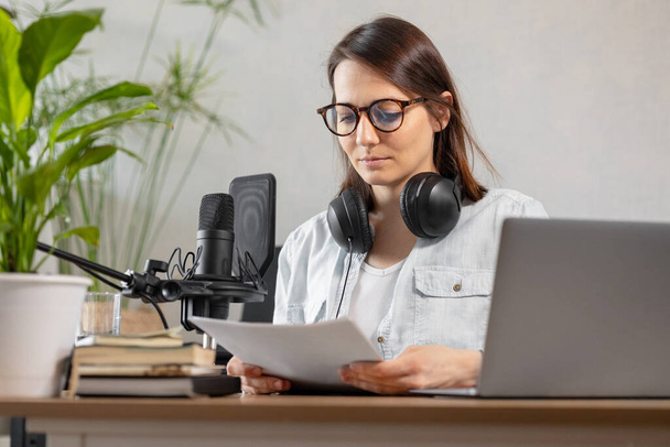 the stylish and educated caucasian woman records podcasts in a recording studio or in her home. the European millennial woman creates audio content or records text, records an audio book or radio show - Foto, Imagem