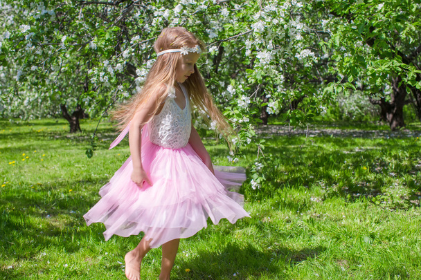 Little cute girl with butterfly wings have fun in blossoming apple orchard - Photo, image