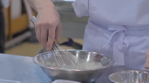 Baker sostiene el batidor de globos y prepara crema dulce batida - Imágenes, Vídeo