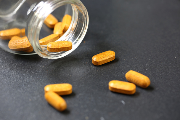 bruine supplement capsule op getextureerde achtergrond - Foto, afbeelding