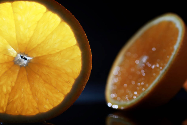 Σύνθεση με φέτες πορτοκαλιού και γκρέιπφρουτ σε μαύρο φόντο. Μια φέτα πορτοκάλι σε μαύρο φόντο με σταγόνες νερού. Ζουμερό πορτοκάλι σε ένα τραπέζι. - Φωτογραφία, εικόνα