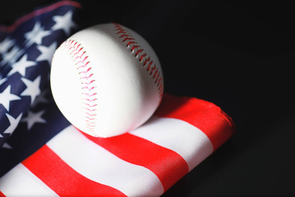 Αμερικάνικο παραδοσιακό αθλητικό παιχνίδι. Μπέιζμπολ. Έννοια. Μπάλα του μπέιζμπολ και ρόπαλα στο τραπέζι με την αμερικανική σημαία. - Φωτογραφία, εικόνα