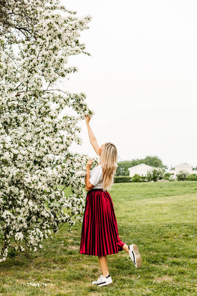 Beautiful girl with light hair, glasses, near flowering trees, Apple tree, spring, branches, flower, fashion, style, European, red - Fotoğraf, Görsel