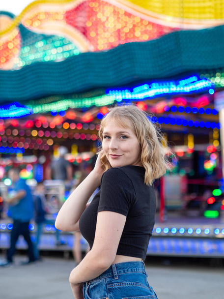 A vertical shot of a blonde woman with a piercing posing in an amusement park - Fotoğraf, Görsel