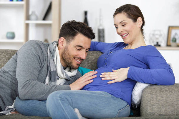 young happy couple expecting baby on sofa - Foto, Imagem