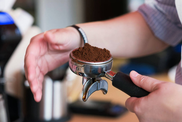 Coffee bean grinder. Ground coffee powder with both hands. Coffee powder is in the handle of the coffee machine. - Фото, зображення