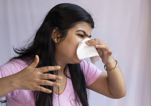 Eine indische Asiatin niest vor laufender Nase auf weißem Hintergrund - Foto, Bild