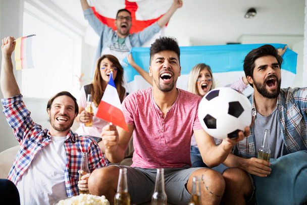 Excited and happy fans of soccer friends celebrating winning match at home - 写真・画像
