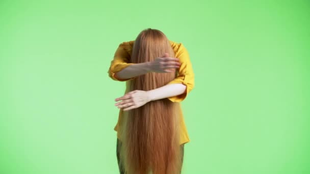 Жінка має своє імбирне волосся на обличчі, тримаючи їх, погладжуючи і складаючи руки перед ними. Зелений фон
 - Кадри, відео