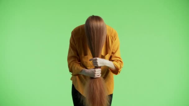 Woman is having her ginger hair on face, holding them, stroking and wounding them around the wrist. Green background - Footage, Video