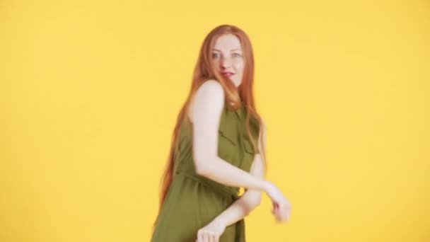 Jeune femme aux cheveux longs et gingembre étonnants dansant et bougeant ses cheveux. Fond jaune. Femme danse en s'amusant - Séquence, vidéo