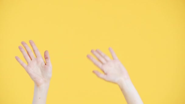 Τα γυναικεία χέρια "χορεύουν" κουνώντας παλάμες και δείχνοντας τα δάχτυλα προς τα πάνω χειρονομία στο κίτρινο φόντο - Πλάνα, βίντεο
