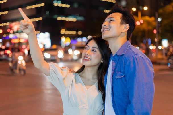 Young Asian couple walking on the street at night - Foto, afbeelding