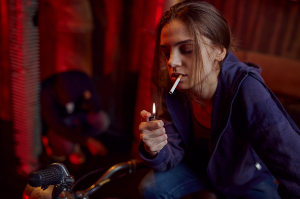 Наркоманка курит сигарету в кабинете, наркоман с ломкой на заднем плане. Проблема наркомании, вечная депрессия наркоманов - Фото, изображение