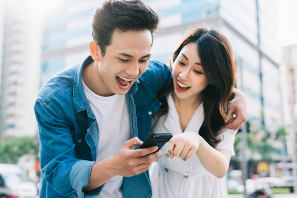Молодая азиатская пара использует смартфон вместе на улице - Фото, изображение