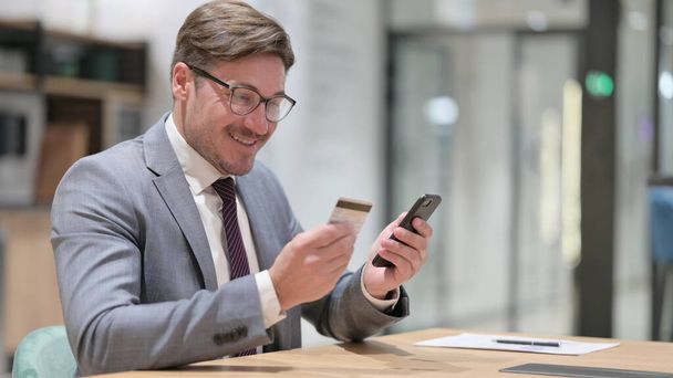 Liikemies, jolla onnistunut online-maksu älypuhelimella toimistossa - Valokuva, kuva