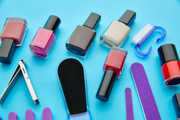 Nail care products, color polish in bottles on blue background, nobody. Healthcare procedures concept, fashion cosmetic, manicure and pedicure tools - Photo, Image