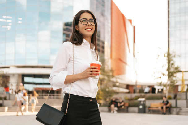 Mujer con camisa blanca sosteniendo un café para llevar - Foto, imagen