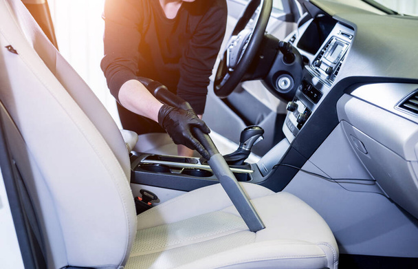 Worker cleans car interior with vacuum cleaner - Φωτογραφία, εικόνα