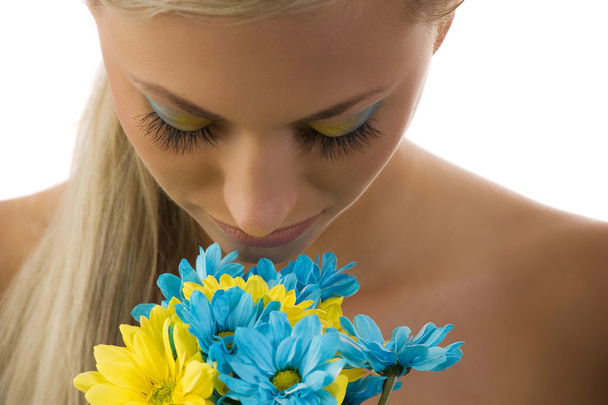 cute blond woman with colored make up in act to smell some daisy - Foto, Imagem