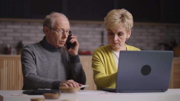 Rentner rufen bei Bank oder Dienstleistungsunternehmen an, um nach Stromrechnungen und Zahlungen zu fragen, alte Ehepartner zahlen online - Filmmaterial, Video
