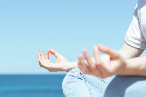 lähikuva naisen käsistä meditoimassa ulkona meren rannalla. - Valokuva, kuva